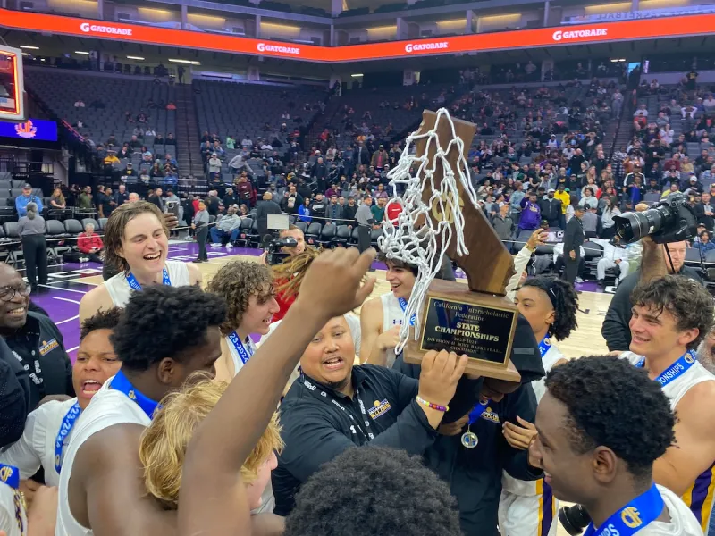 Oakland Tech boys basketball team celebrating a CIF State Championship with the trophy net.